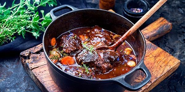 Saftiges Stück Fleisch mit Beilagen gärt im Dutch Oven