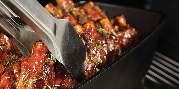Grillgut wird mit Grillzange ausgerichtet