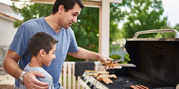 Vater und Sohn grillen zusammen Würste